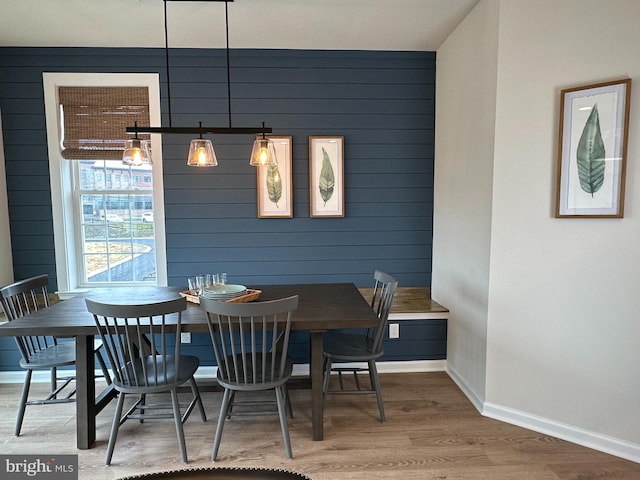 dining room featuring wood-type flooring and wood walls