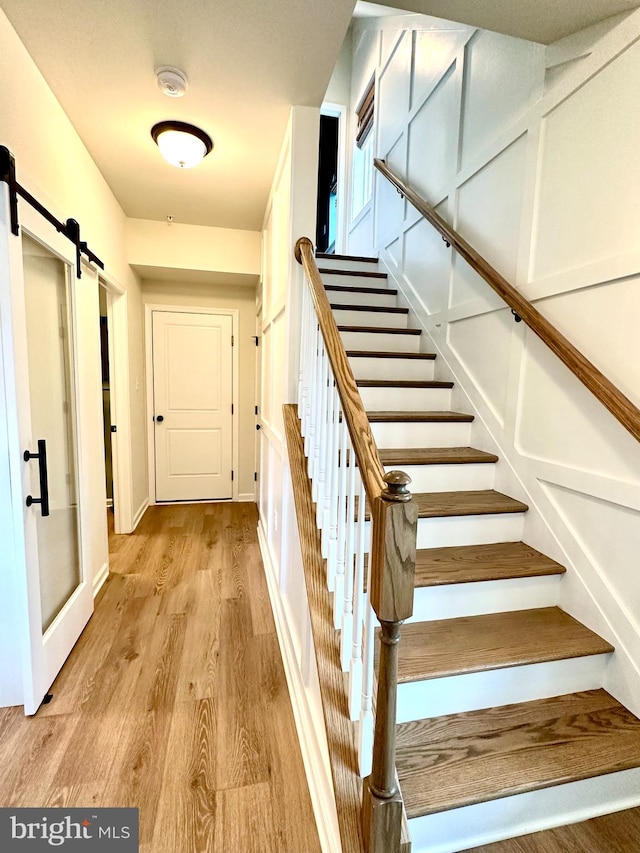 staircase featuring a barn door and hardwood / wood-style flooring