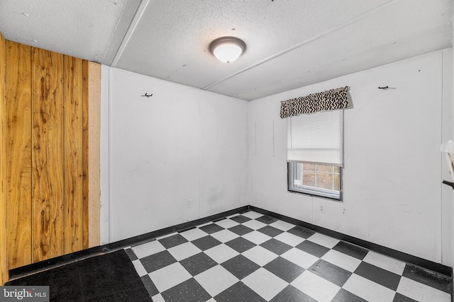 empty room with a textured ceiling and wooden walls