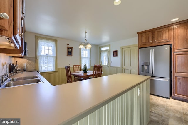 kitchen with sink, hanging light fixtures, stainless steel fridge with ice dispenser, kitchen peninsula, and a chandelier