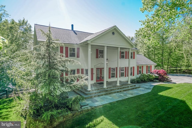 rear view of house featuring a yard and covered porch