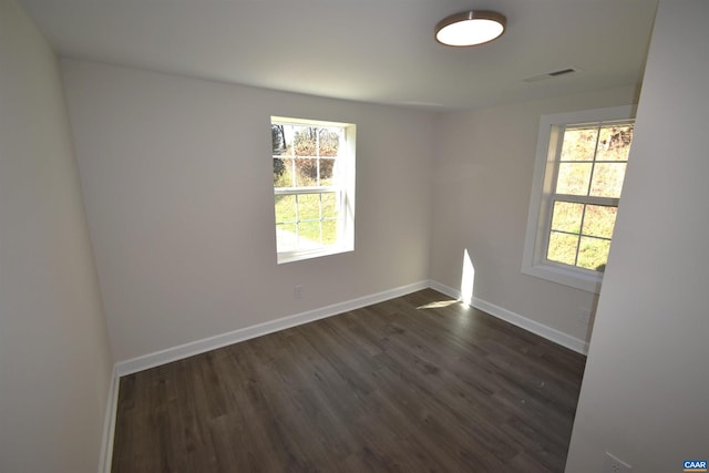 unfurnished room with a healthy amount of sunlight and dark hardwood / wood-style flooring