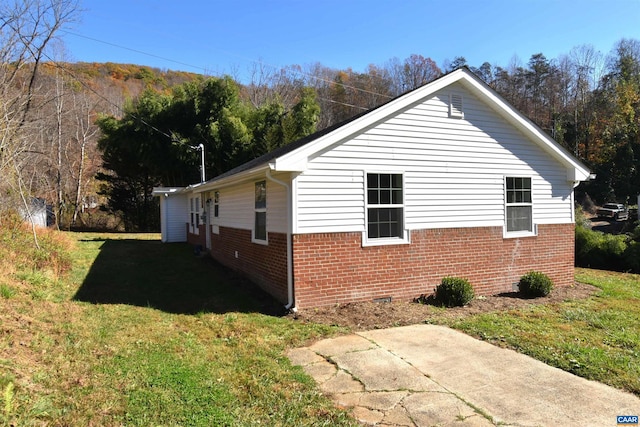 view of side of home with a patio and a lawn