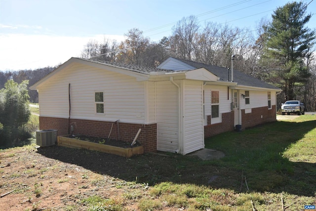 view of side of home with central AC and a lawn