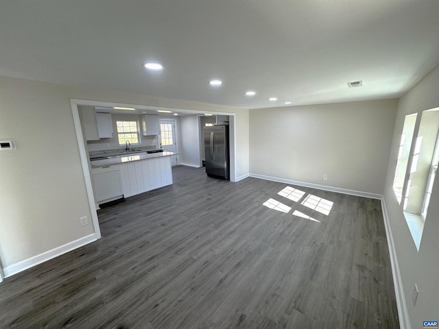 kitchen featuring stainless steel fridge, sink, white cabinetry, and dark wood-type flooring