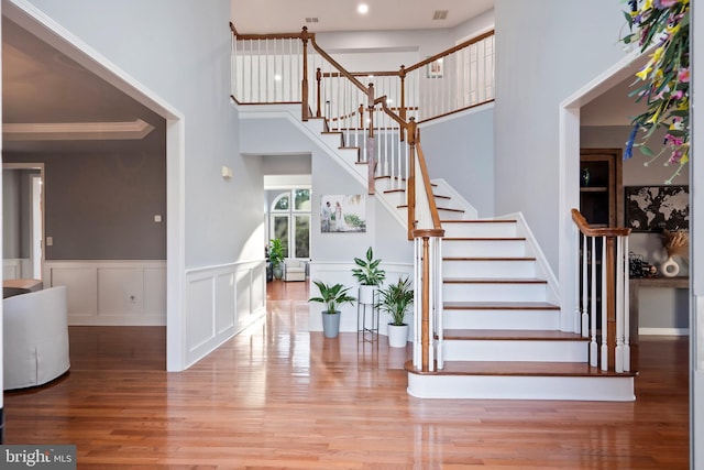 stairway featuring hardwood / wood-style floors, a towering ceiling, and crown molding