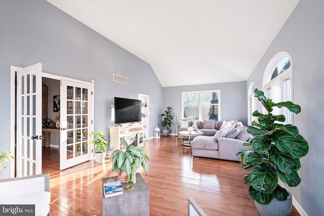 living room with french doors, high vaulted ceiling, and wood-type flooring