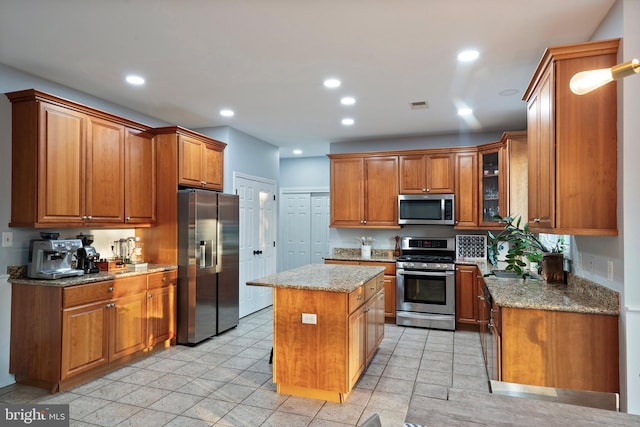 kitchen with a center island, stainless steel appliances, and light stone counters