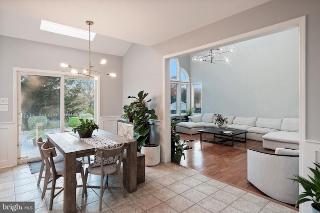 dining area featuring a chandelier, light hardwood / wood-style flooring, lofted ceiling with skylight, and a healthy amount of sunlight