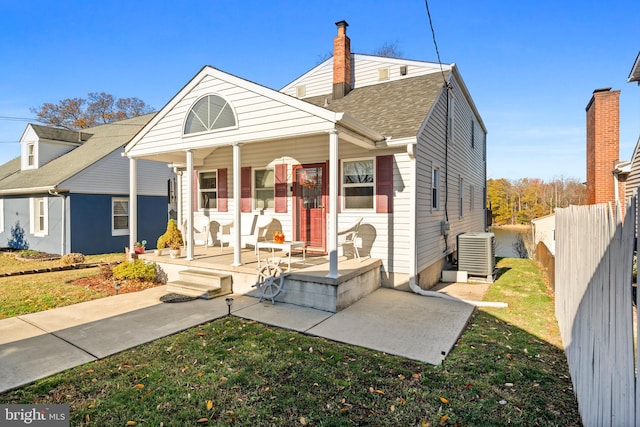 view of front of house with cooling unit, covered porch, and a front lawn