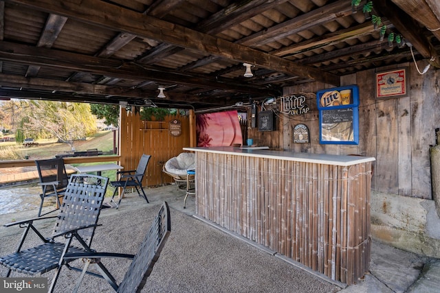 bar featuring carpet flooring, wood walls, beamed ceiling, and wooden ceiling