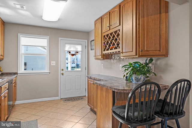 kitchen with stainless steel dishwasher, a breakfast bar, and light tile patterned floors