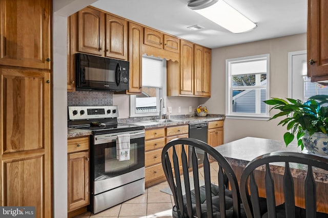 kitchen featuring sink, light tile patterned flooring, and black appliances