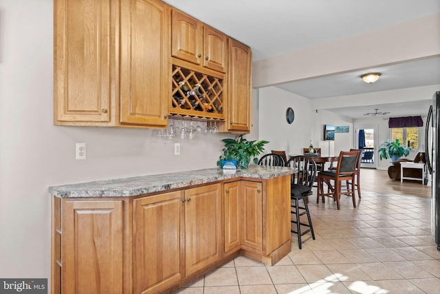 kitchen with ceiling fan, a breakfast bar, and light tile patterned floors