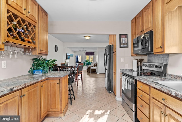 kitchen with black appliances, ceiling fan, light tile patterned floors, and backsplash