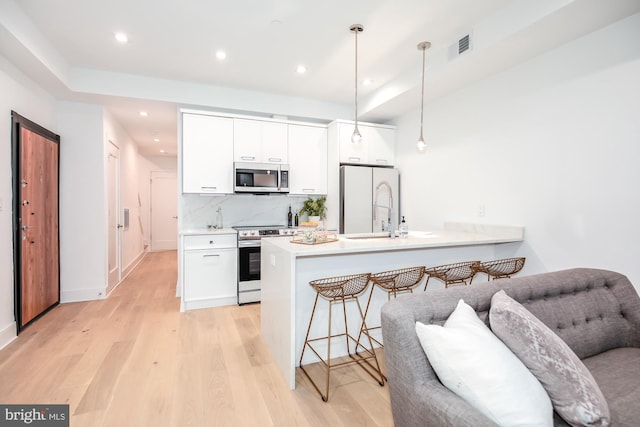 kitchen featuring electric range oven, light hardwood / wood-style floors, white fridge, white cabinetry, and hanging light fixtures