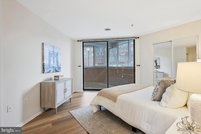 bedroom with light wood-type flooring, access to outside, and a closet