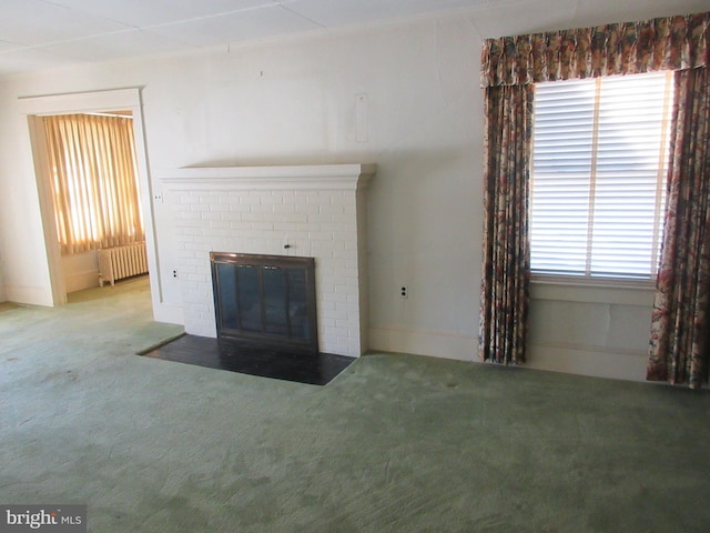 unfurnished living room with radiator, carpet flooring, and a fireplace