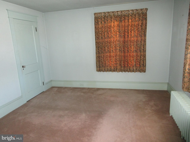 carpeted spare room featuring radiator heating unit