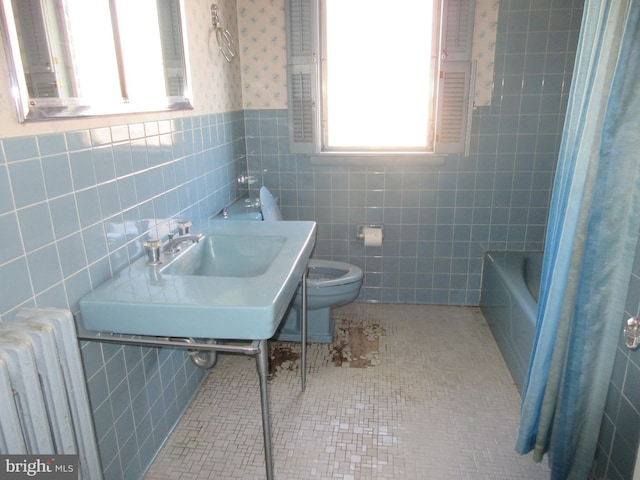 bathroom featuring toilet, tile walls, tile patterned floors, radiator, and sink