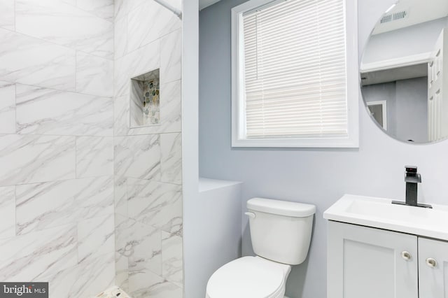 bathroom with vanity, toilet, and tiled shower