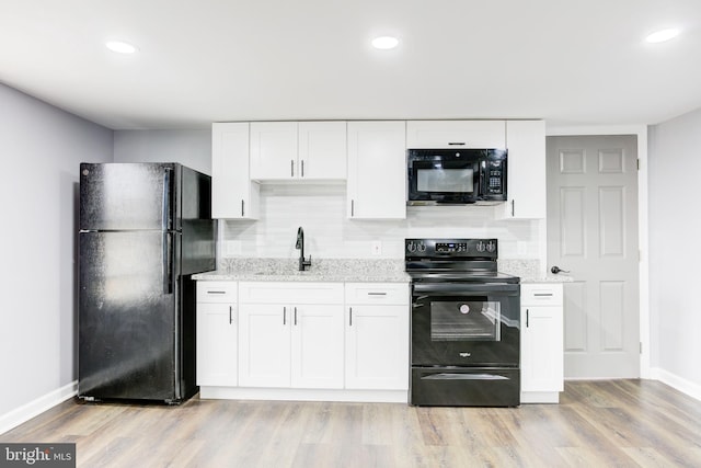 kitchen featuring decorative backsplash, light wood-type flooring, white cabinetry, and black appliances