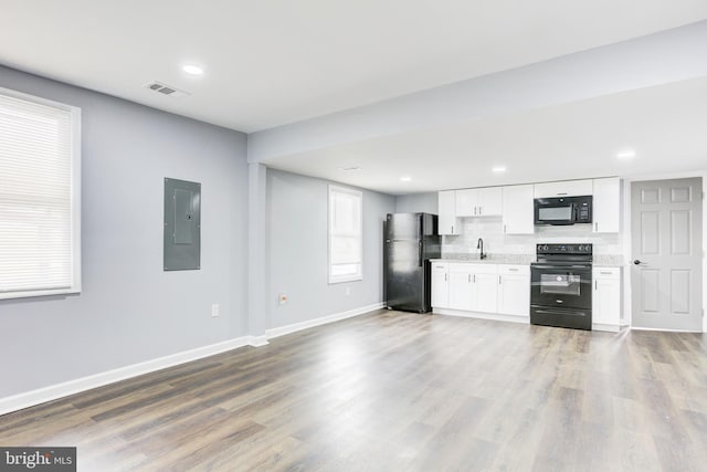 kitchen featuring electric panel, white cabinetry, hardwood / wood-style floors, and black appliances