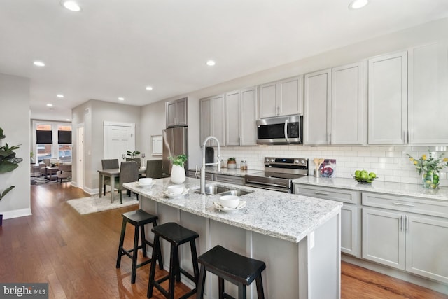 kitchen featuring appliances with stainless steel finishes, dark hardwood / wood-style floors, a kitchen island with sink, and sink