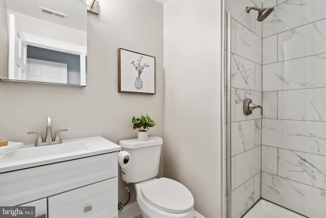 bathroom featuring vanity, toilet, and a tile shower