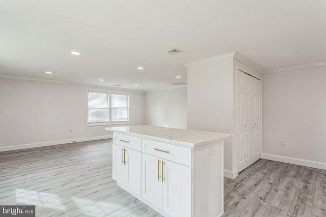 kitchen with a center island, light stone countertops, ornamental molding, light hardwood / wood-style floors, and white cabinetry