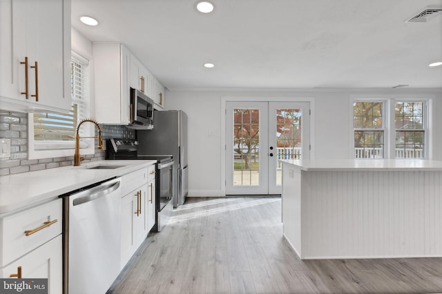 kitchen featuring french doors, tasteful backsplash, stainless steel appliances, sink, and white cabinets