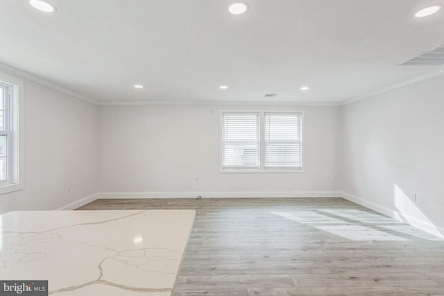 unfurnished room featuring crown molding, plenty of natural light, and light hardwood / wood-style floors