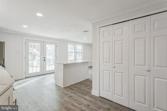 kitchen featuring french doors, a center island, light hardwood / wood-style floors, and ornamental molding