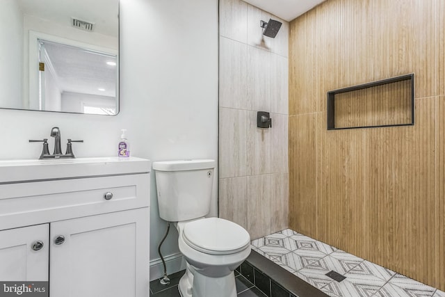 bathroom with tile patterned floors, toilet, vanity, and tiled shower