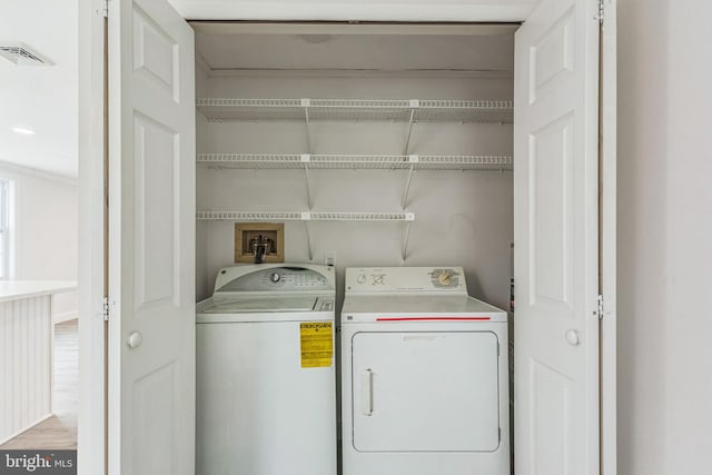 laundry area featuring washing machine and clothes dryer and light wood-type flooring