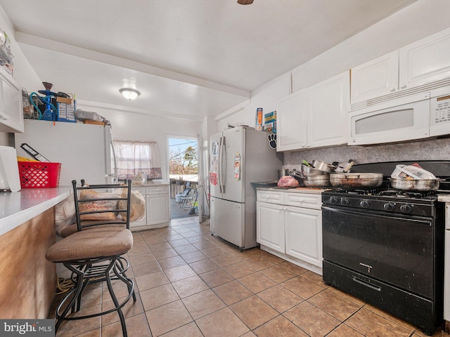 kitchen with stainless steel fridge, black range with gas stovetop, and white cabinets