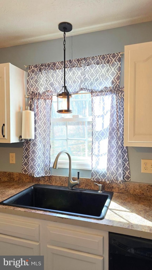 kitchen with sink, light stone countertops, black dishwasher, decorative light fixtures, and white cabinetry