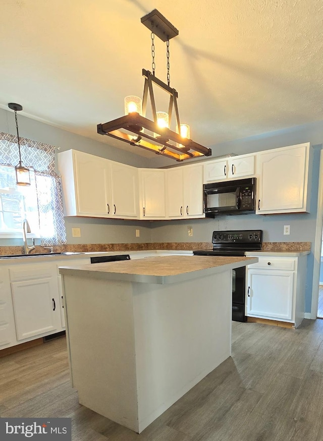 kitchen featuring white cabinetry, dark wood-type flooring, black appliances, and decorative light fixtures