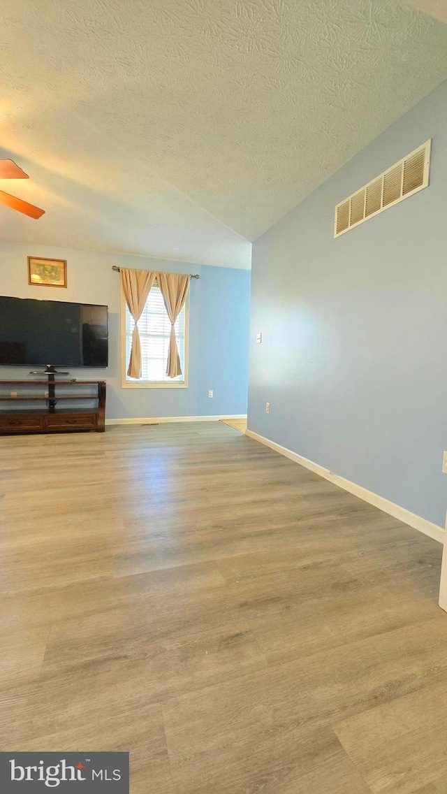 interior space with a textured ceiling, light wood-type flooring, and ceiling fan