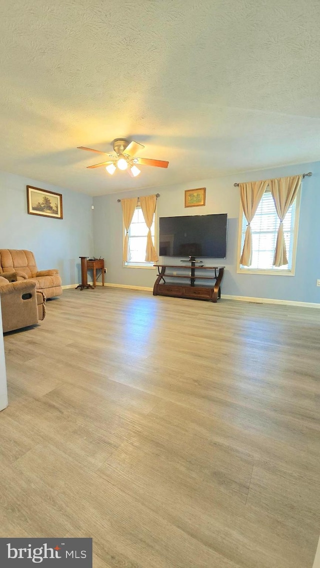 interior space with ceiling fan, a textured ceiling, and light hardwood / wood-style flooring