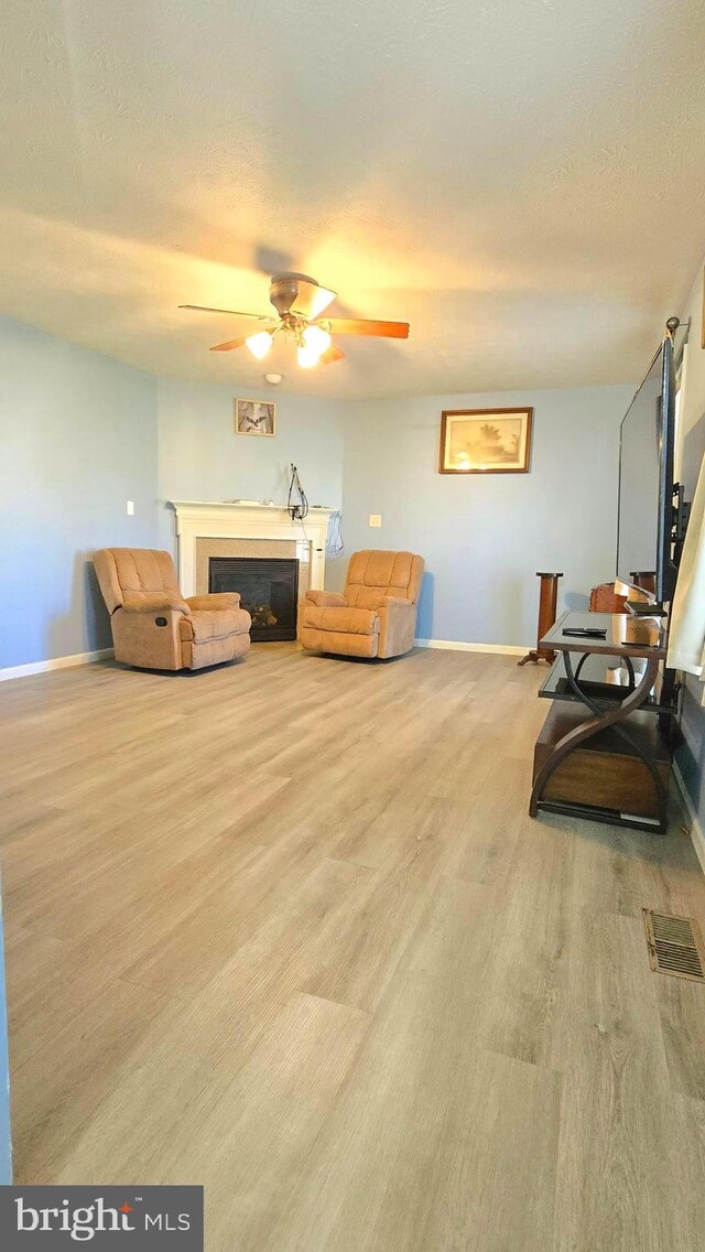 sitting room featuring a textured ceiling, light hardwood / wood-style flooring, and ceiling fan