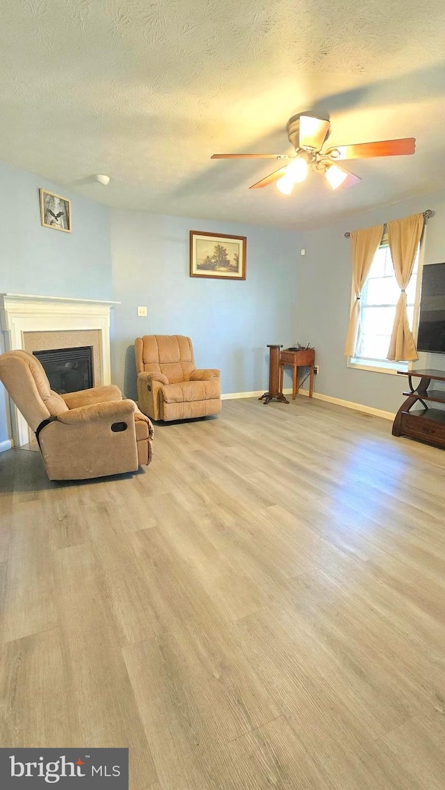 living area with a textured ceiling, light hardwood / wood-style floors, and ceiling fan