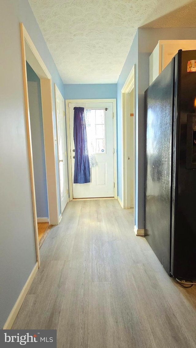 corridor with light hardwood / wood-style floors and a textured ceiling