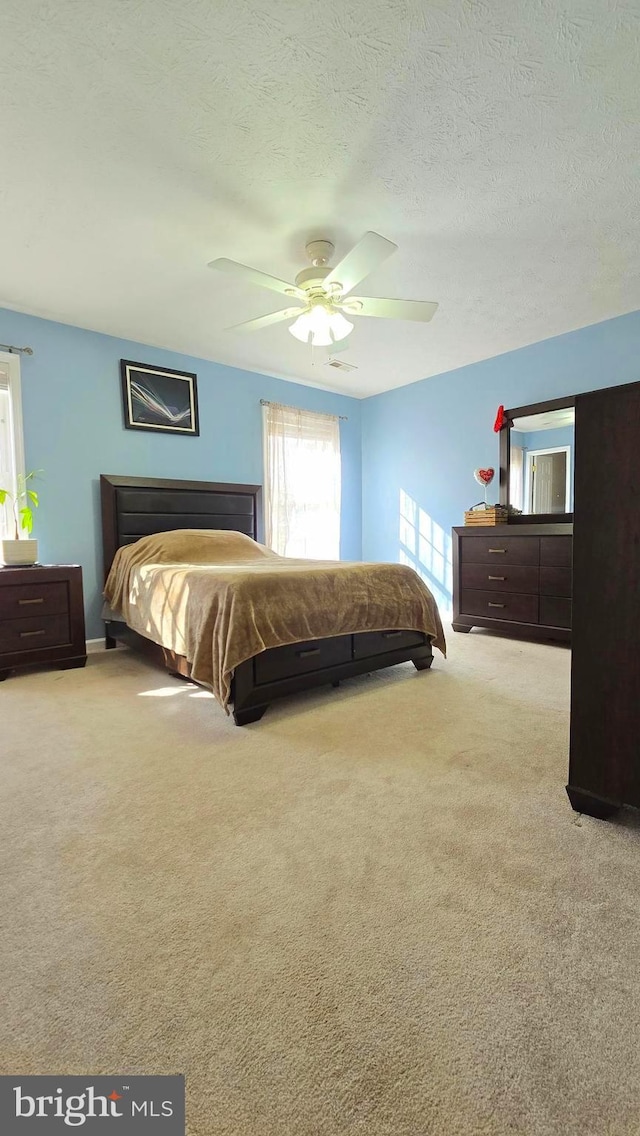 carpeted bedroom with a textured ceiling and ceiling fan