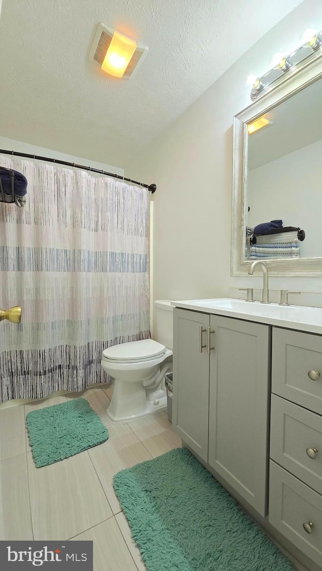 bathroom featuring vanity, toilet, and a textured ceiling