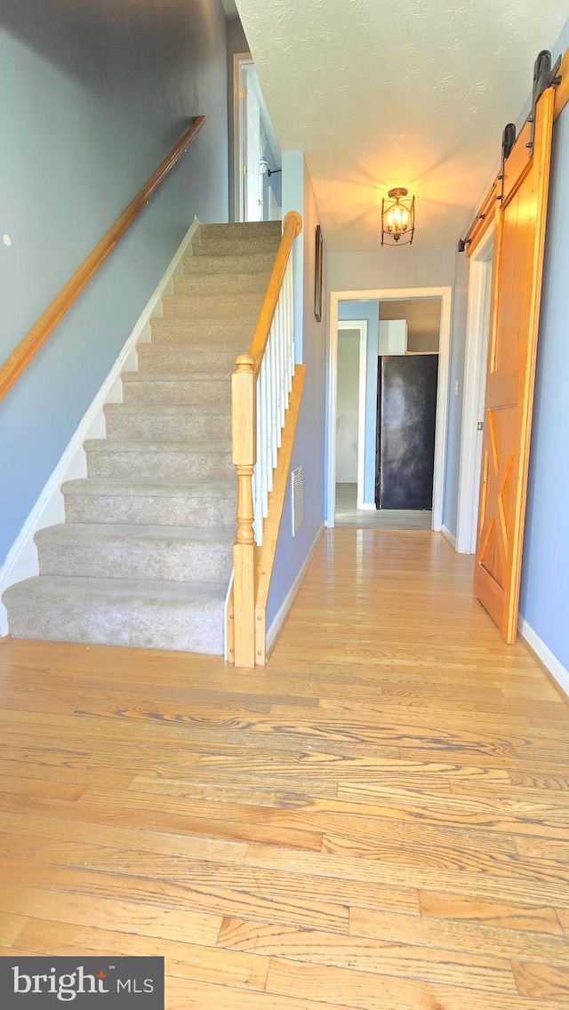 stairway featuring a barn door and hardwood / wood-style flooring