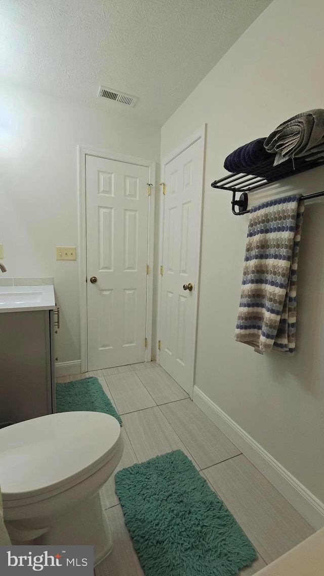 bathroom with vanity, a textured ceiling, and toilet