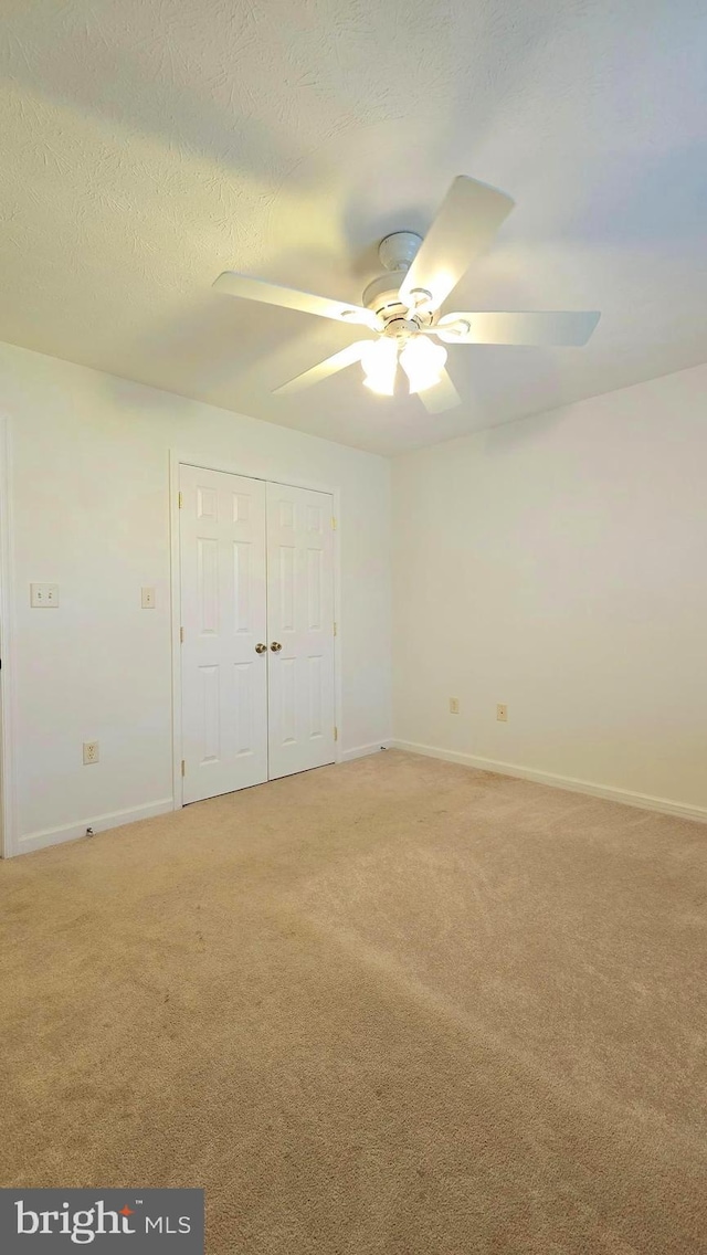 unfurnished bedroom with carpet, ceiling fan, and a textured ceiling