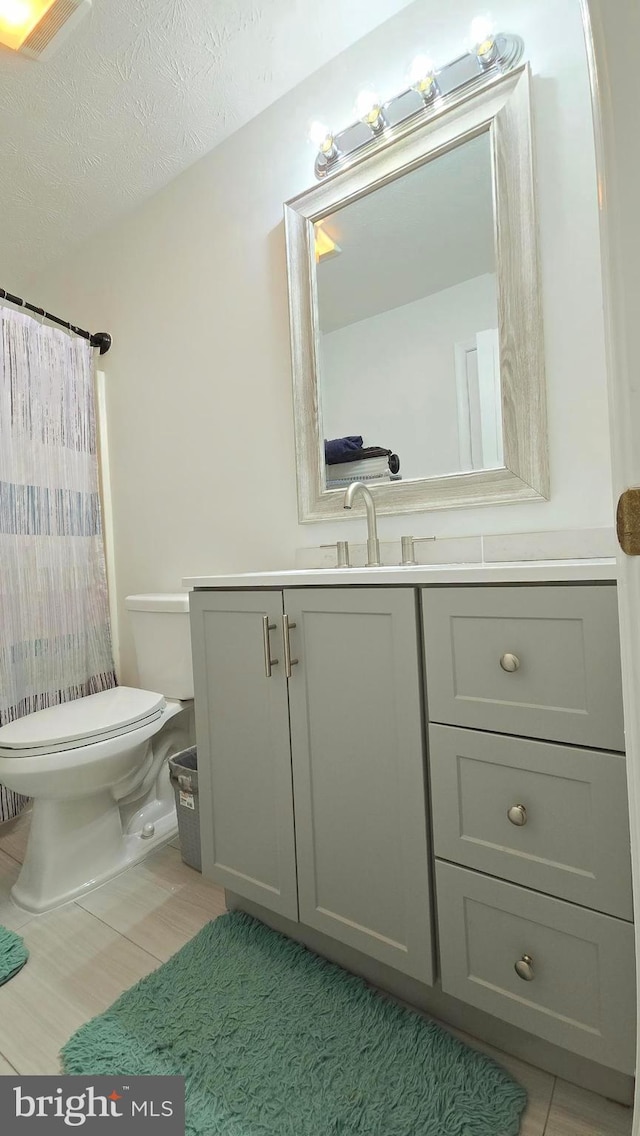 bathroom with vanity, curtained shower, toilet, and a textured ceiling