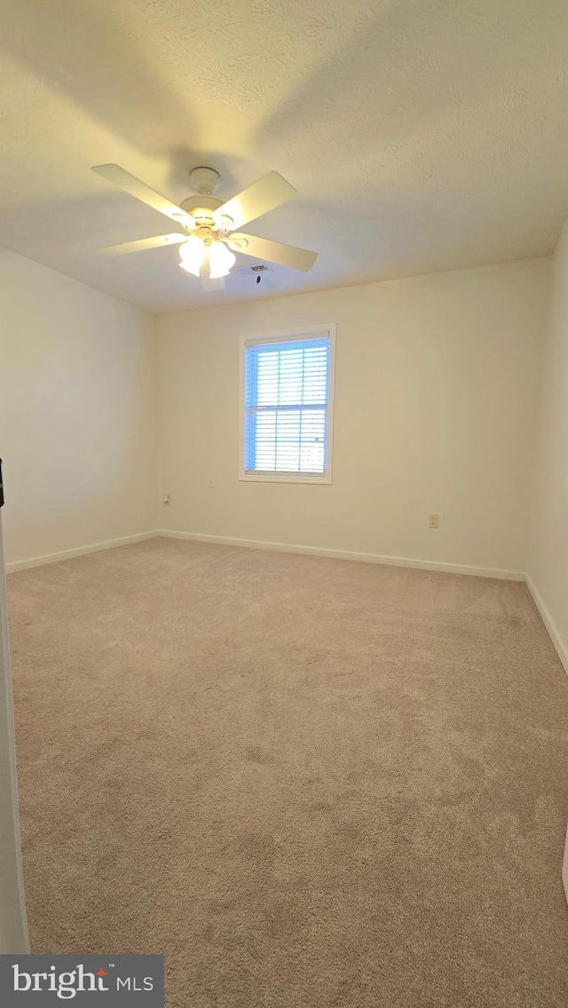 carpeted empty room with ceiling fan and a textured ceiling